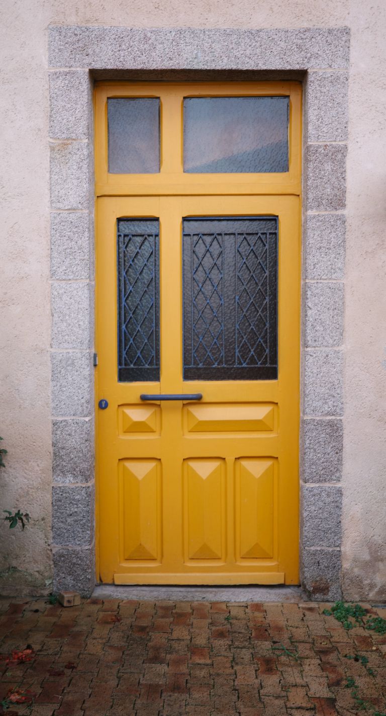 A vibrant yellow door set in a rustic stone facade, adding charm and character.