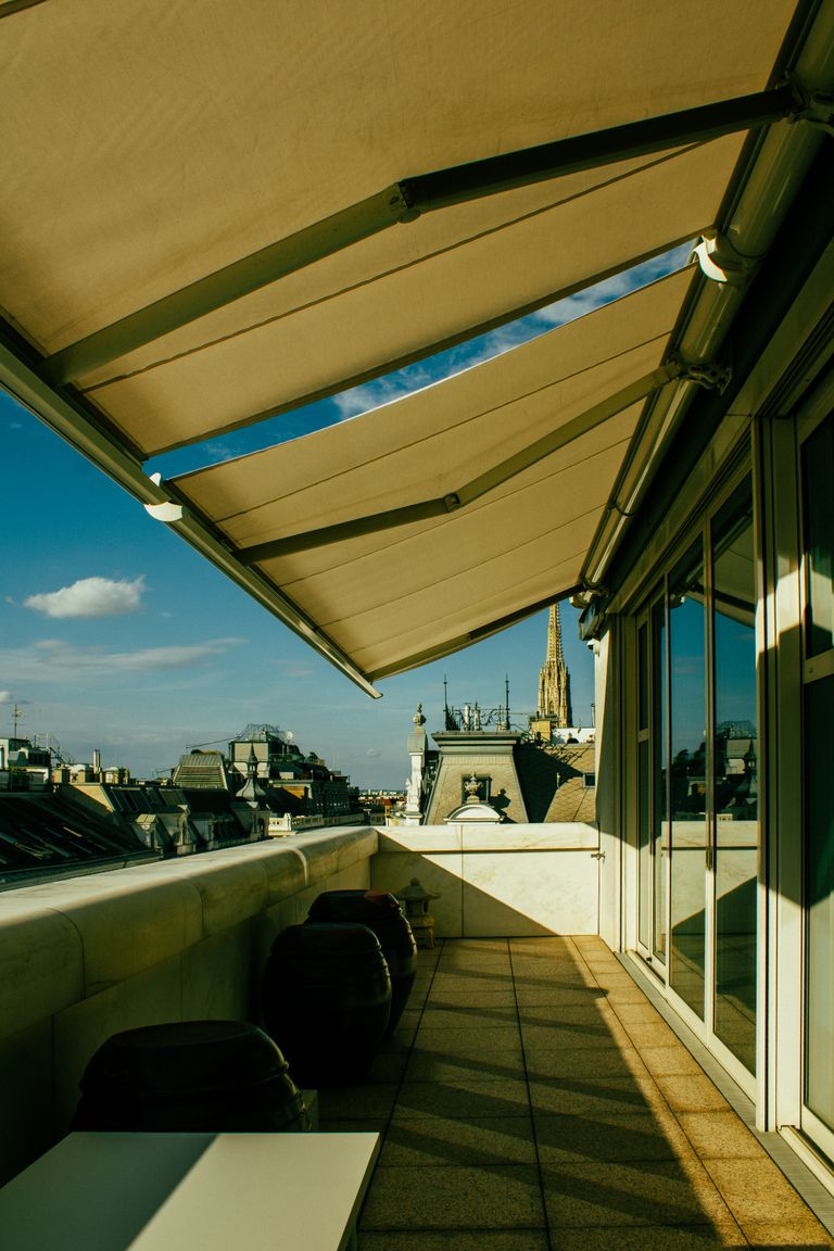 Sunlit balcony with canopy view of city skyline and iconic spires.
